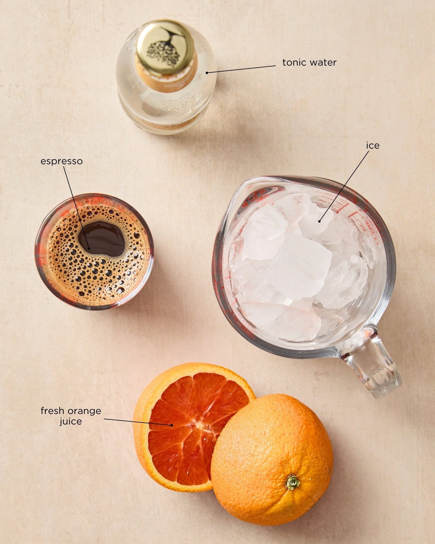 Surface filled with ingredients needed for espresso tonic including tonic water, espresso, and orange.