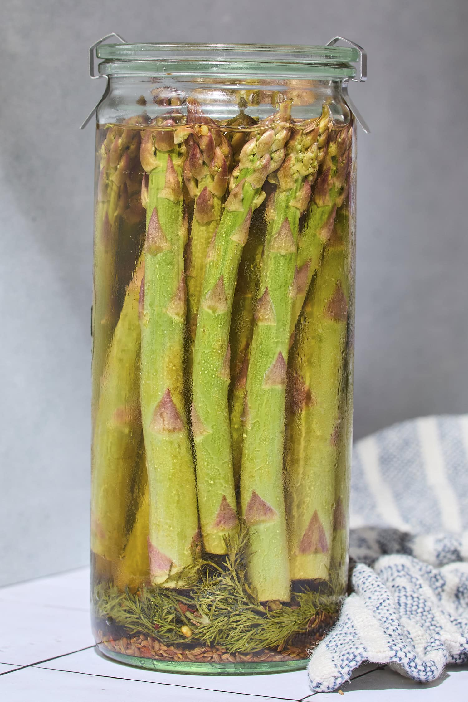 Glass jar filled with spears of asparagus with brine poured on top.