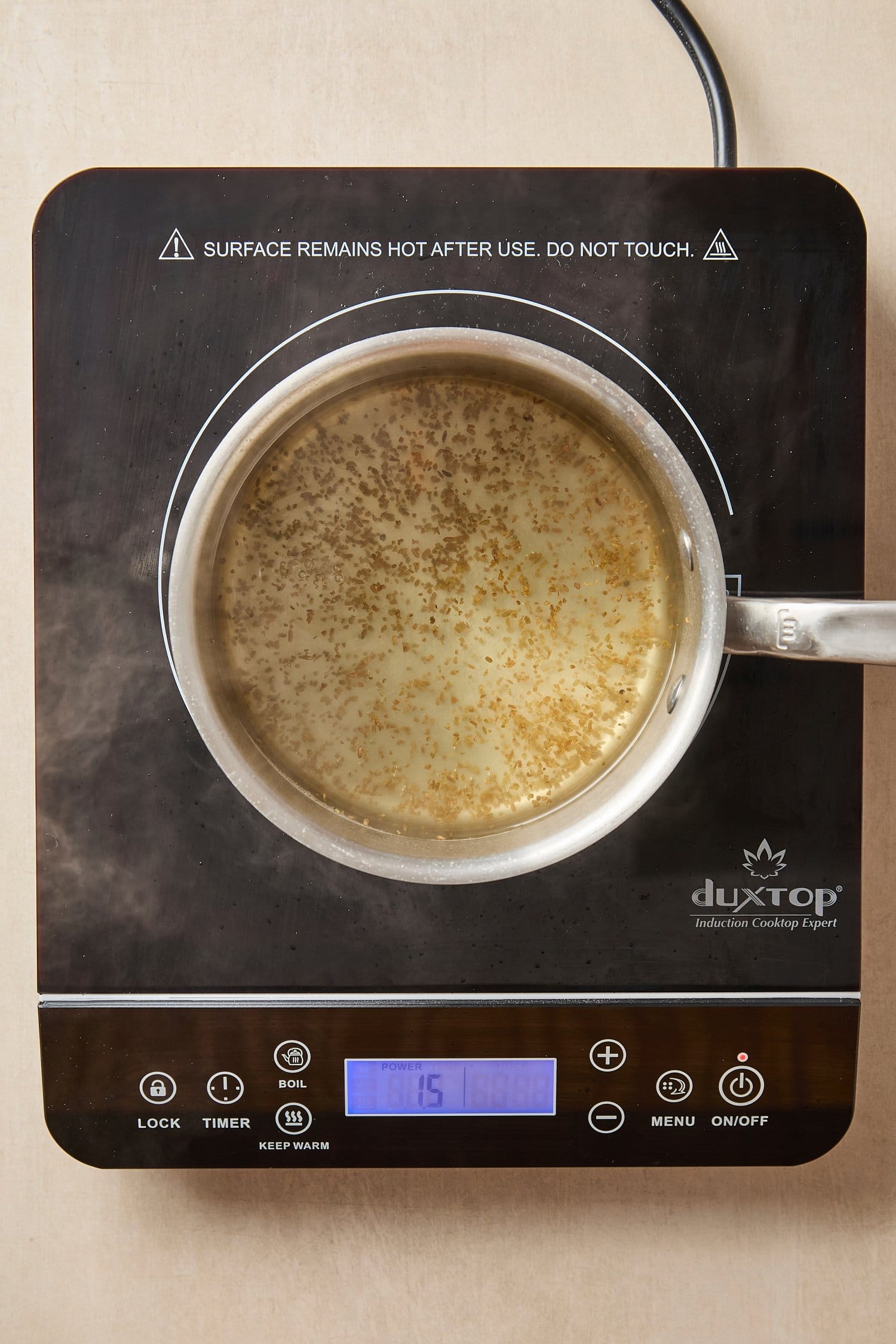 Saucepan with brine with cumin seeds inside heating on hot plate.