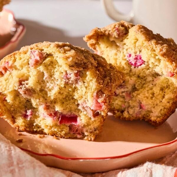 Rhubarb muffin split in half showing red pieces of rhubarb inside.