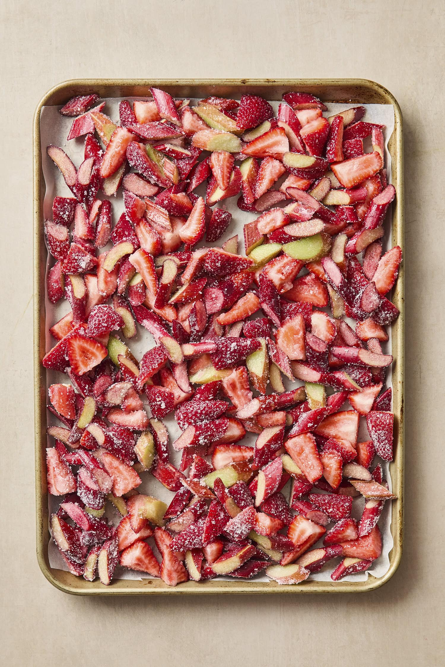 Baking sheet filled with sliced strawberries and chopped rhubarb before roasting.