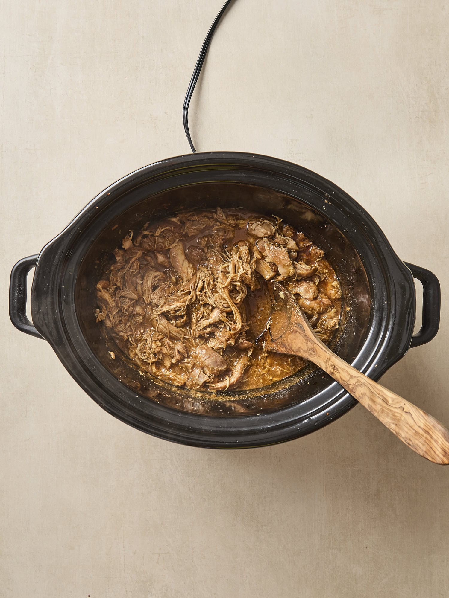 Cooked and shredded chicken taco meat in a slow cooker.