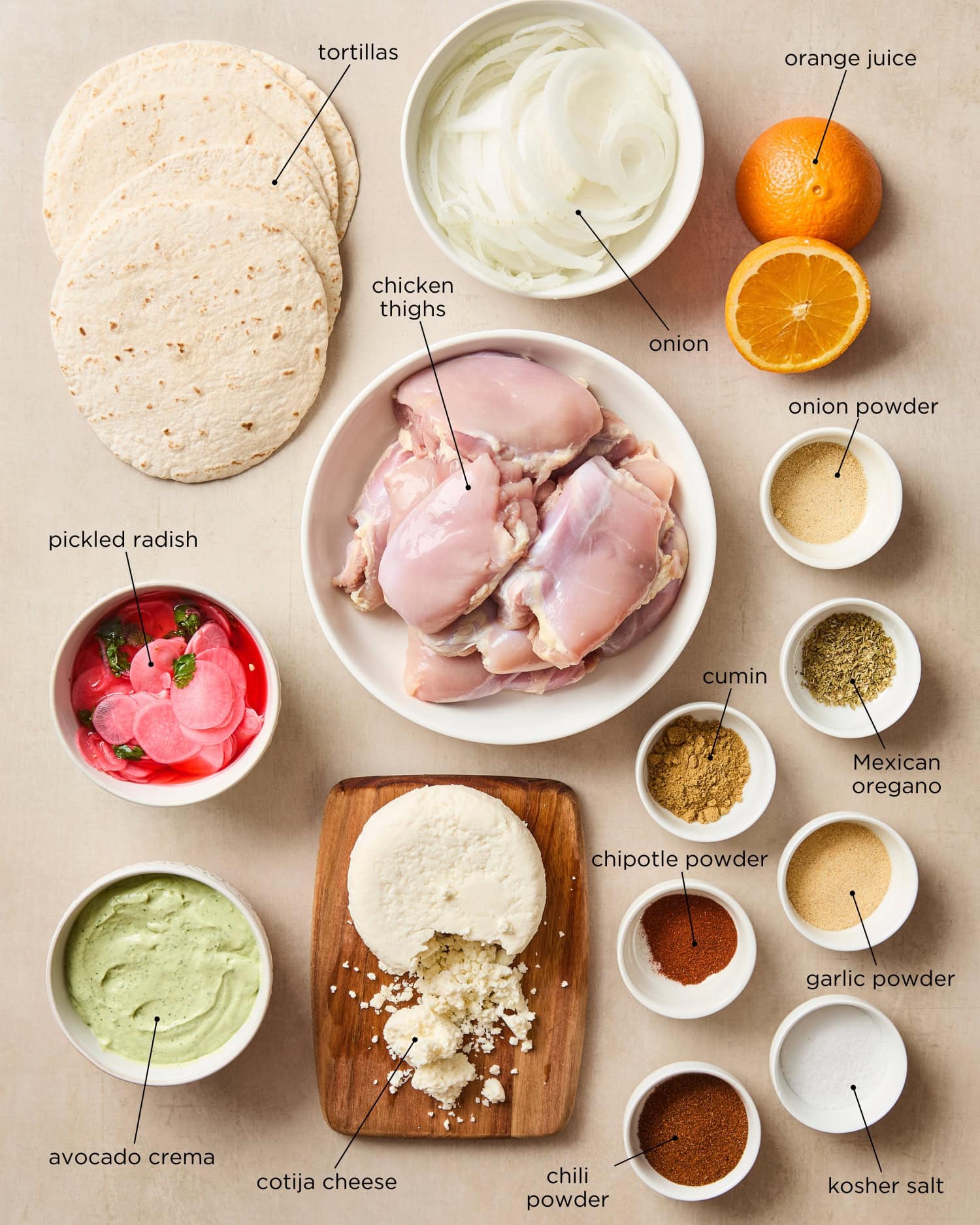Surface filled with ingredients for chicken tacos with spices, cheese, tortillas, chicken thighs, and more.