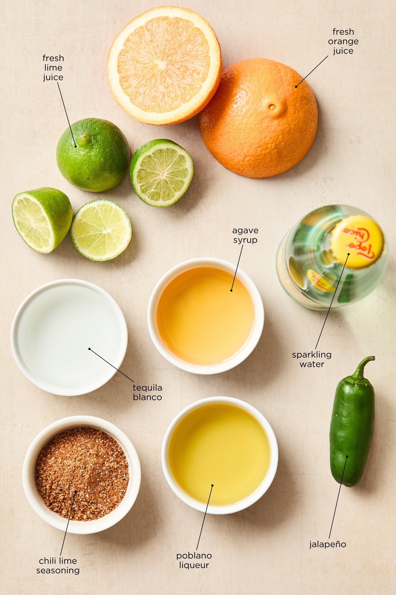 Surface filled with ingredients needed for spicy margarita including liquor, fruit, and more.