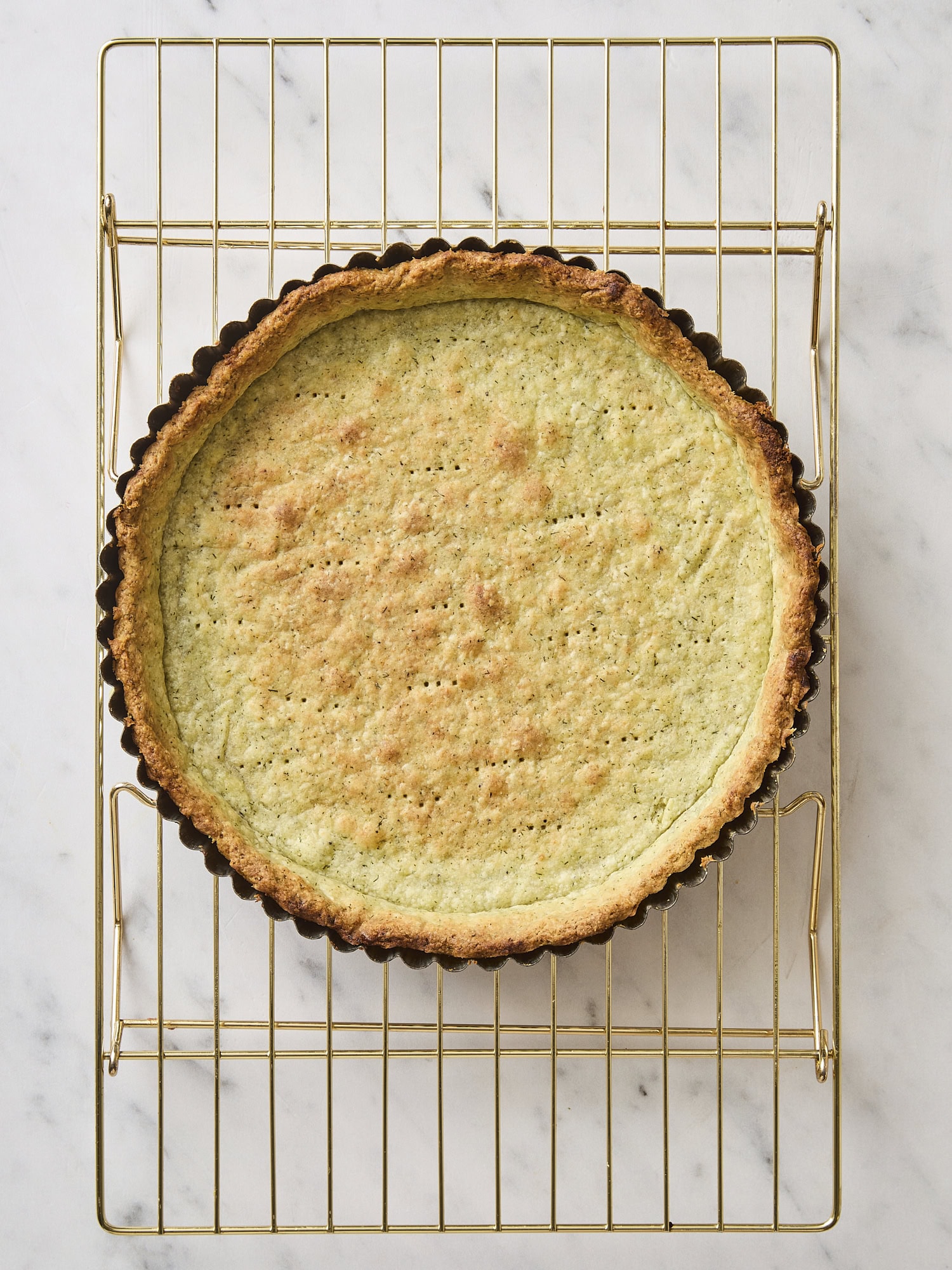 Baked crust with some herbs with golden color on cooling rack.