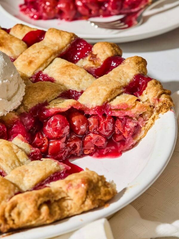Sliced cherry pie showing filling with a lattice crust.