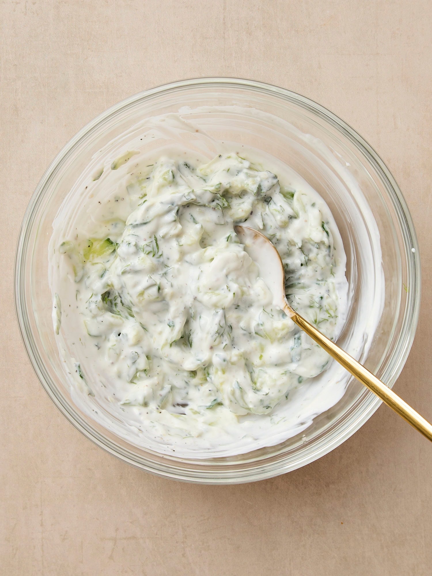 Glass bowl with tzatziki sauce after being mixed together.