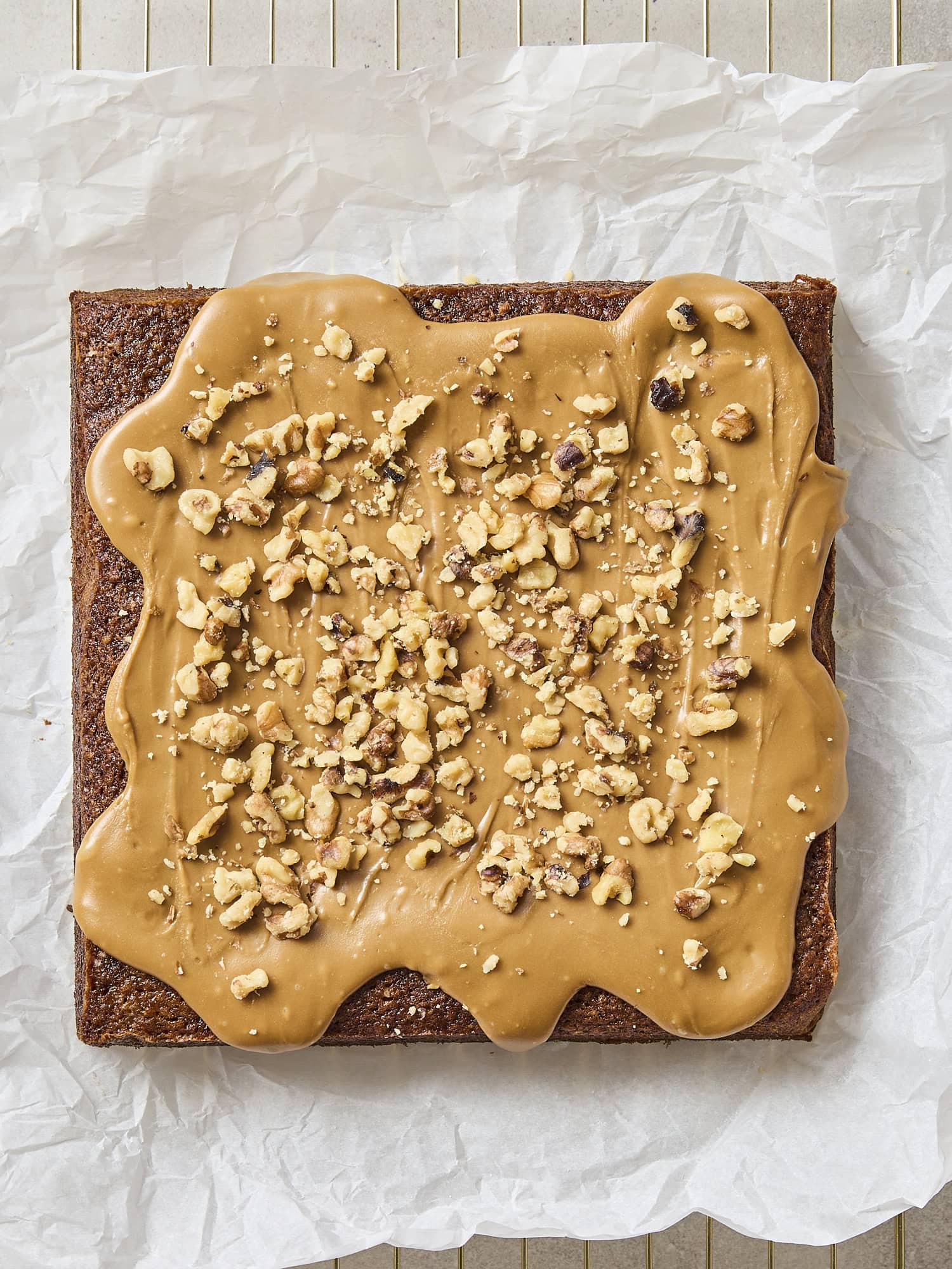 Frosted applesauce cake with walnuts sprinkled on top.
