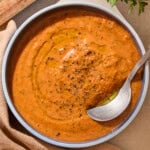Blue bowl with creamy gazpacho soup inside with spoon.
