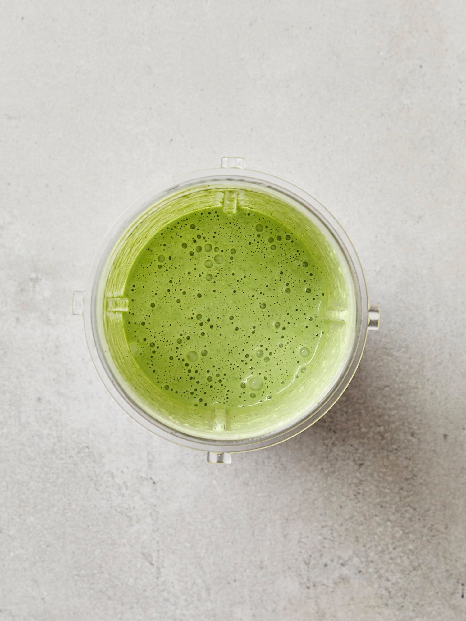 Blender container with blended green salad dressing.