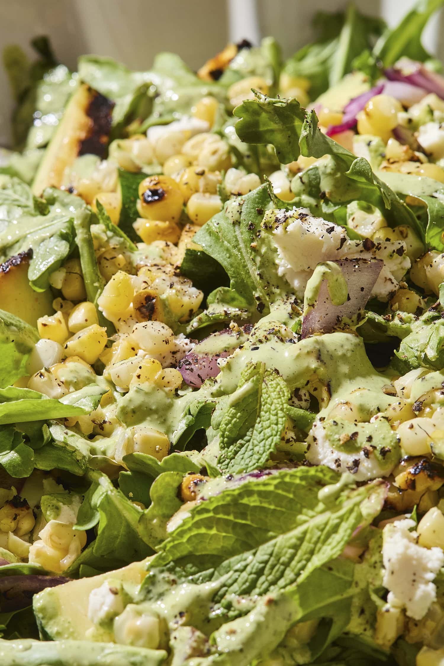 Sweet corn salad with mint leaves, red onion, and zucchini with dressing.