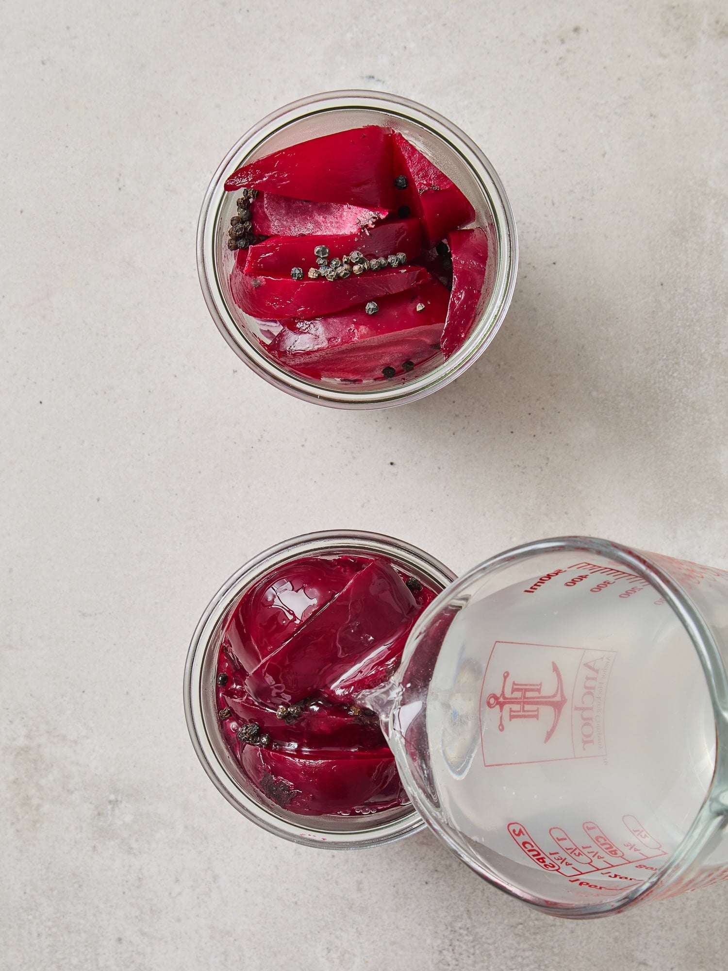 Pouring brine over wedged beets in a preserving jar.