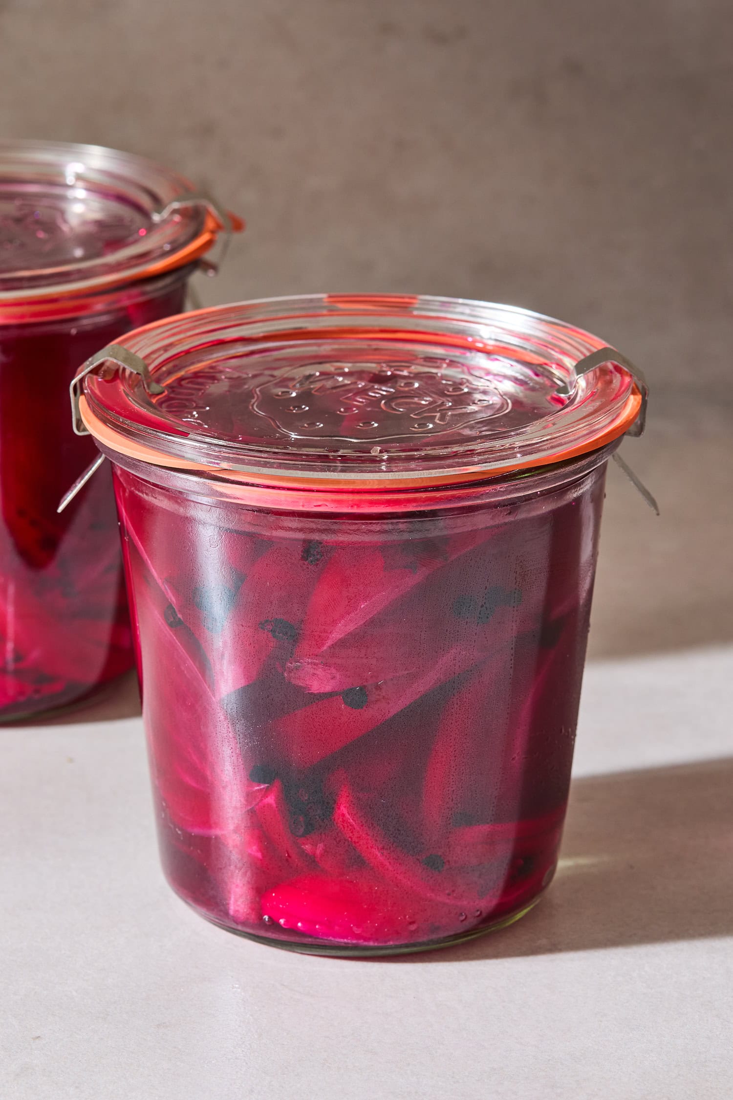 A jar with quick-pickled beets on a concrete surface.