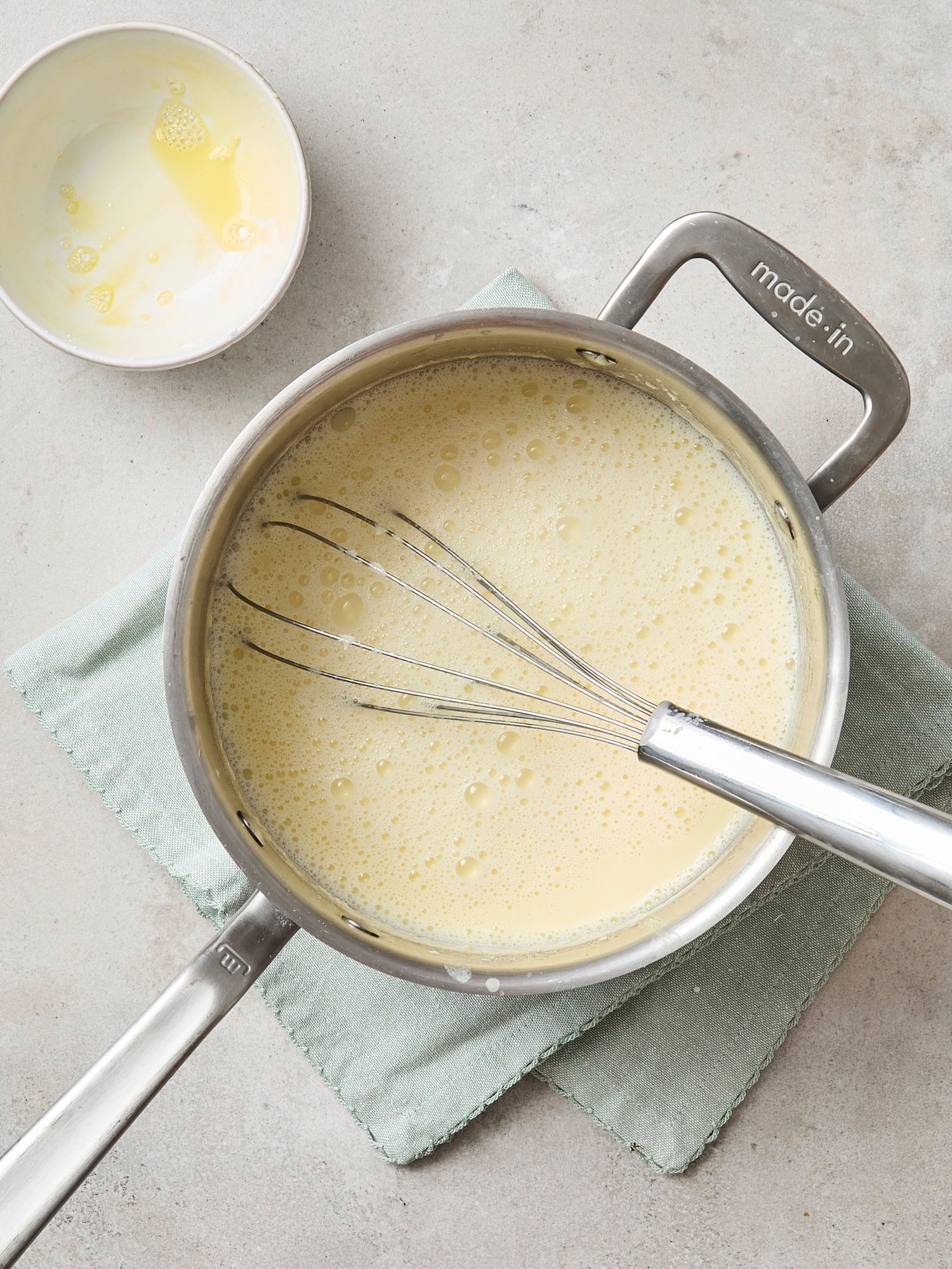 Saucepan with milk base for ice cream after cornstarch slurry is whisked in.