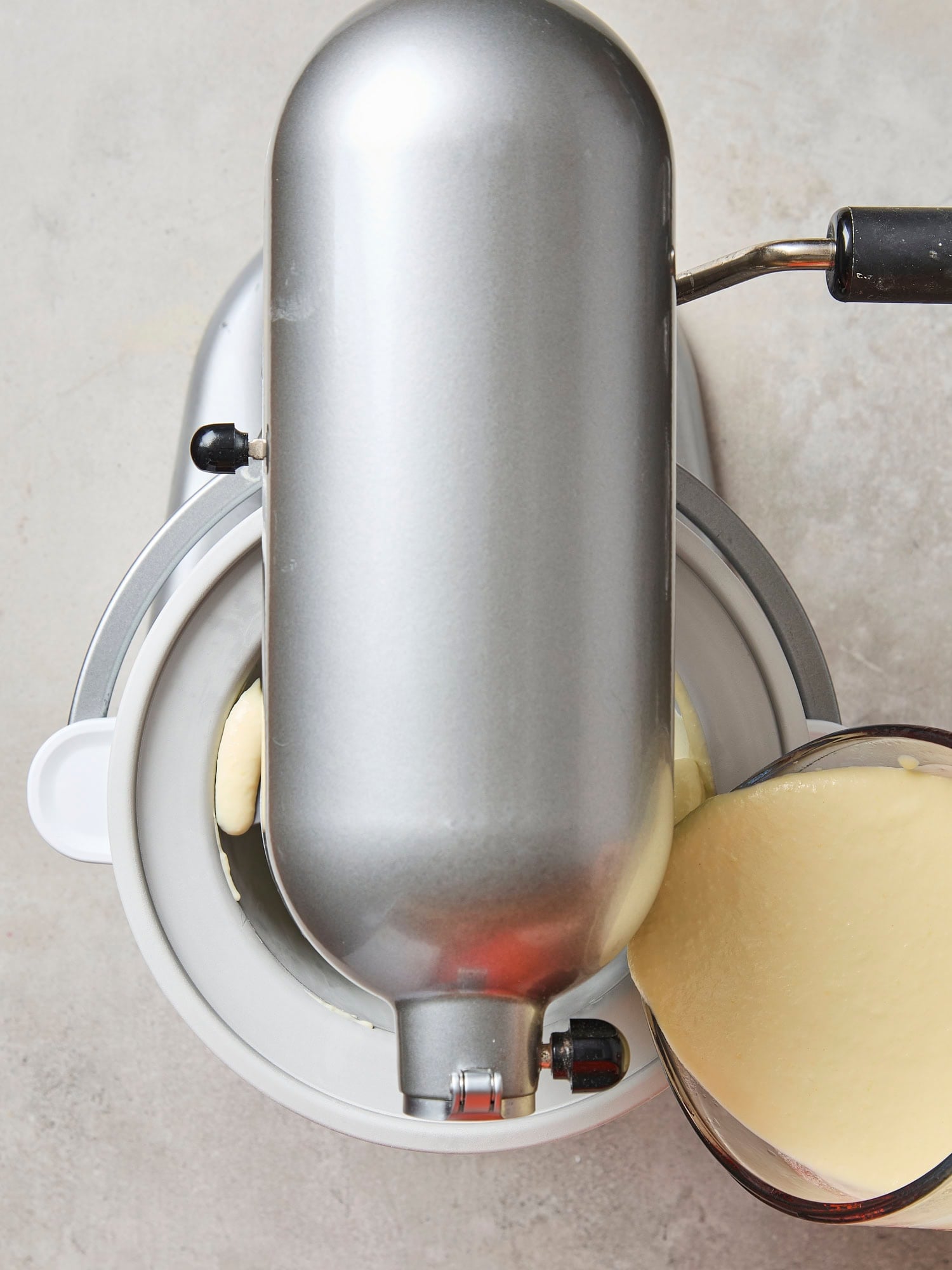 Stand mixer ice cream maker with sweet corn ice cream being poured into container.