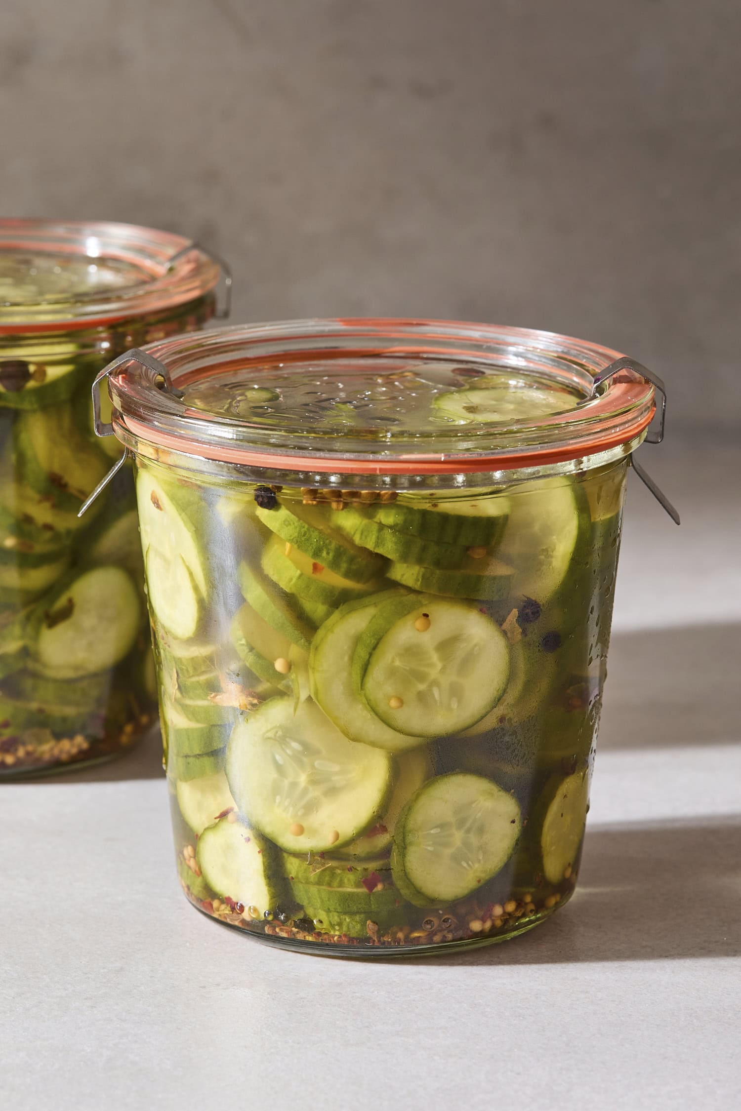 Weck jar filled with slices of sweet pickles with another jar behind.