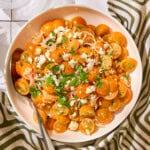 Bowl with yellow cherry tomatoes topped with feta cheese and parsley for a quick tomato salad.