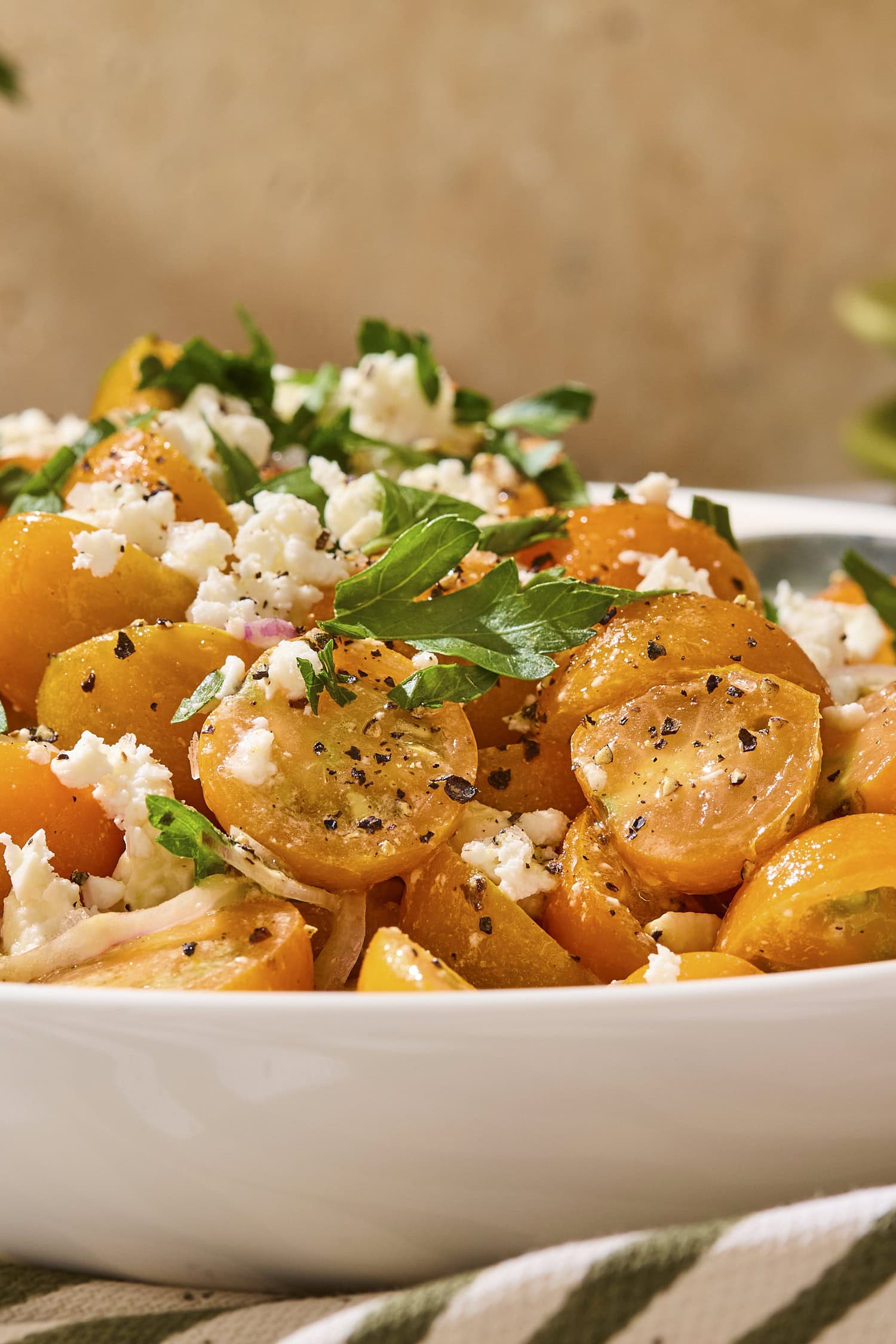 Sungold cherry tomatoes in a bowl with feta and parsley on top.