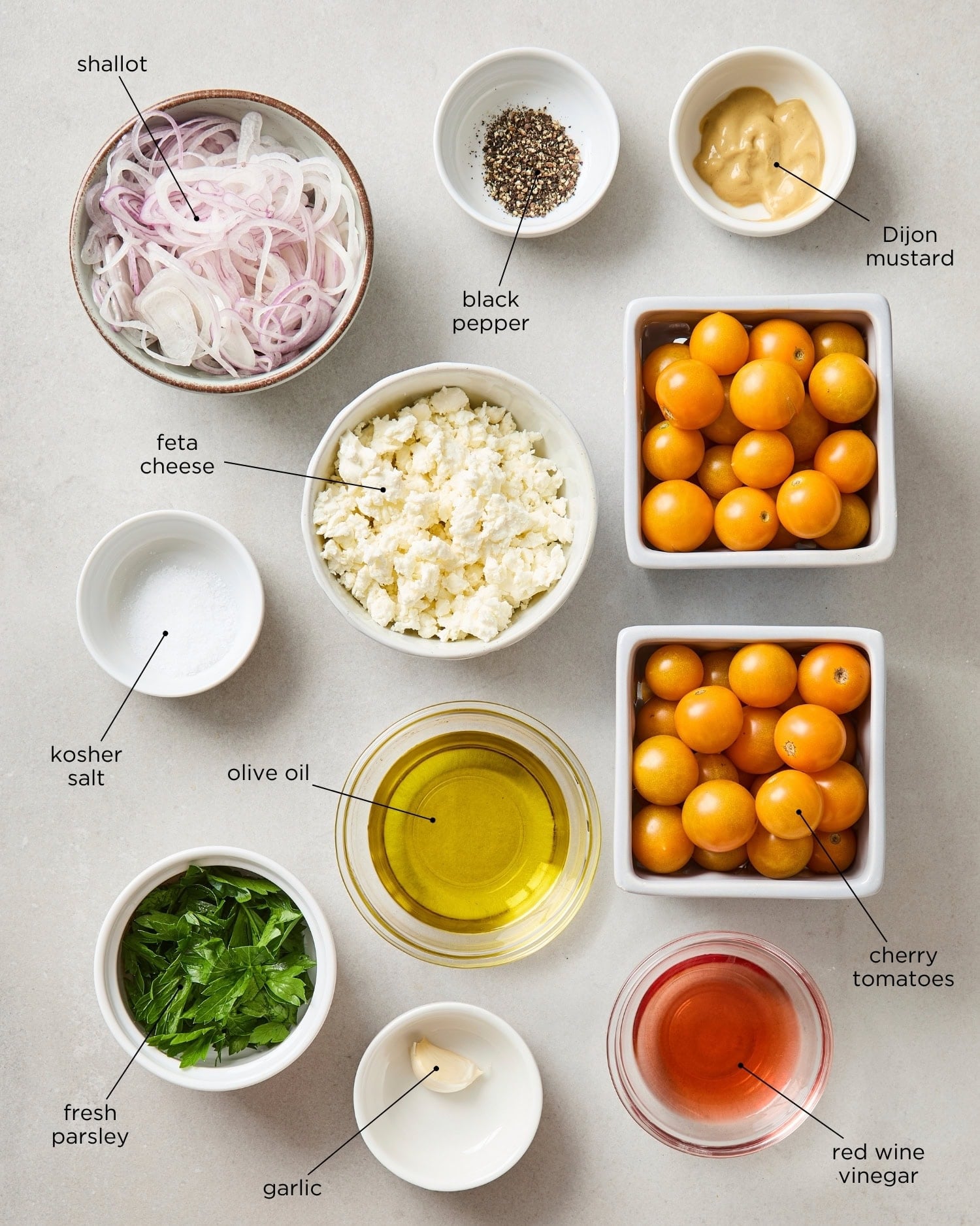 Surface with ingredients for tomato salad including tomatoes, shallot, and items for a dressing.
