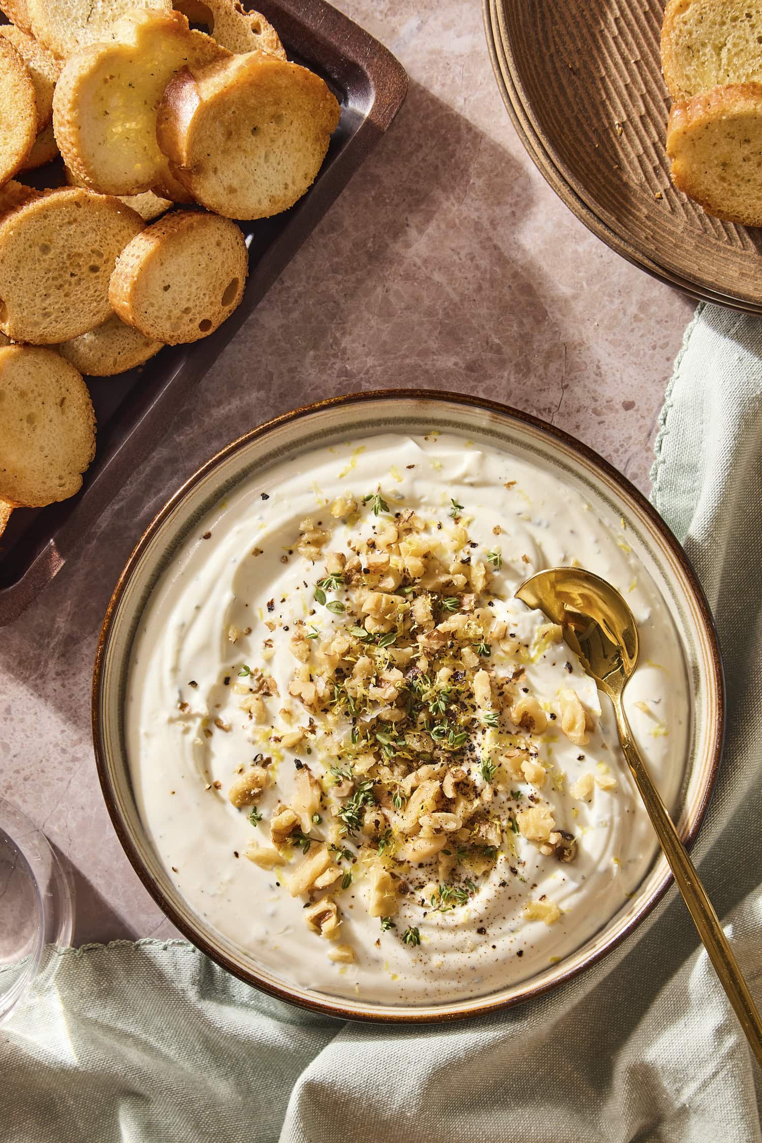 Bowl filled with whipped ricotta dip topped with walnuts and thyme.