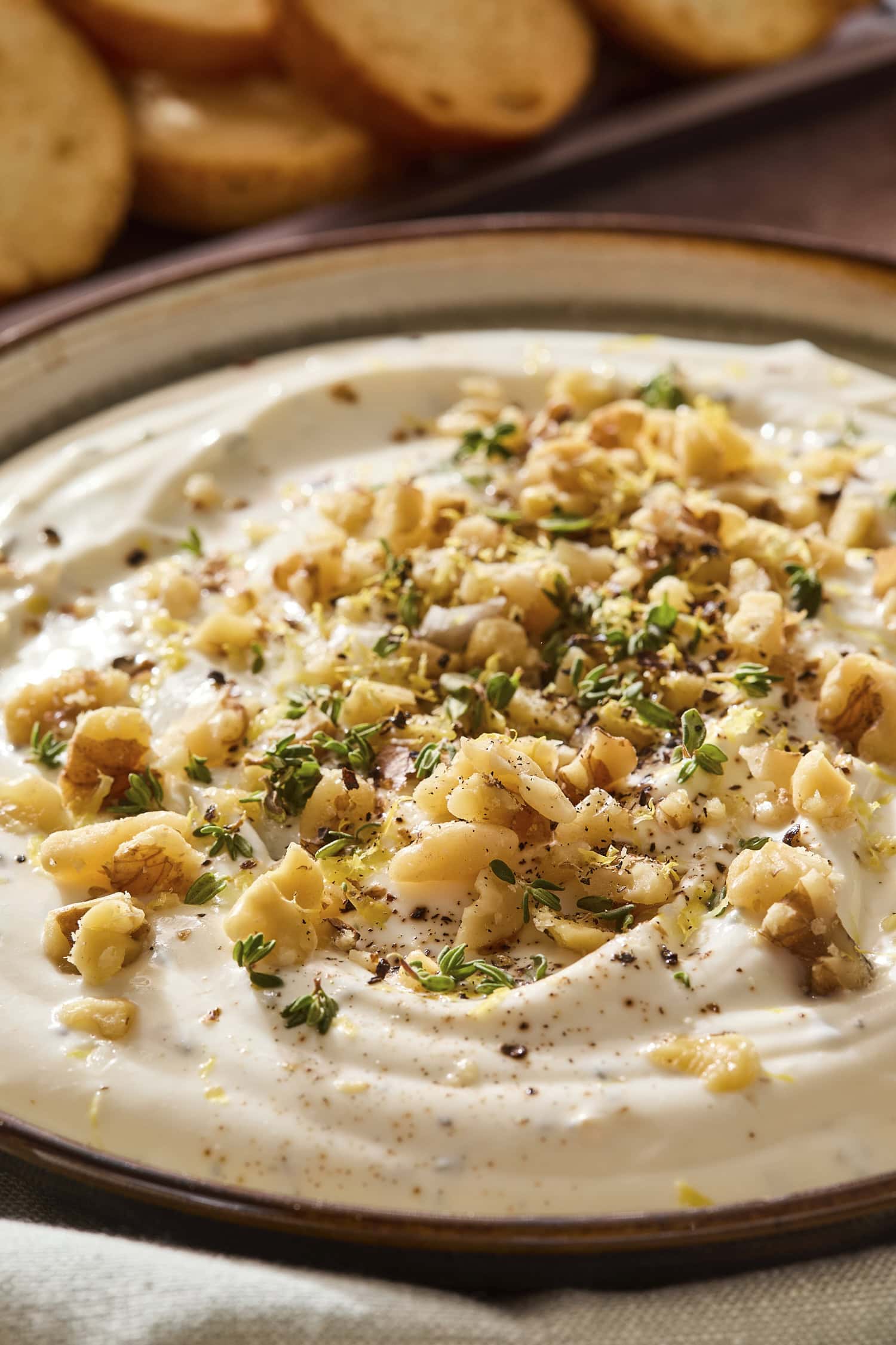 Chopped walnuts and thyme on top of whipped ricotta cheese dip.