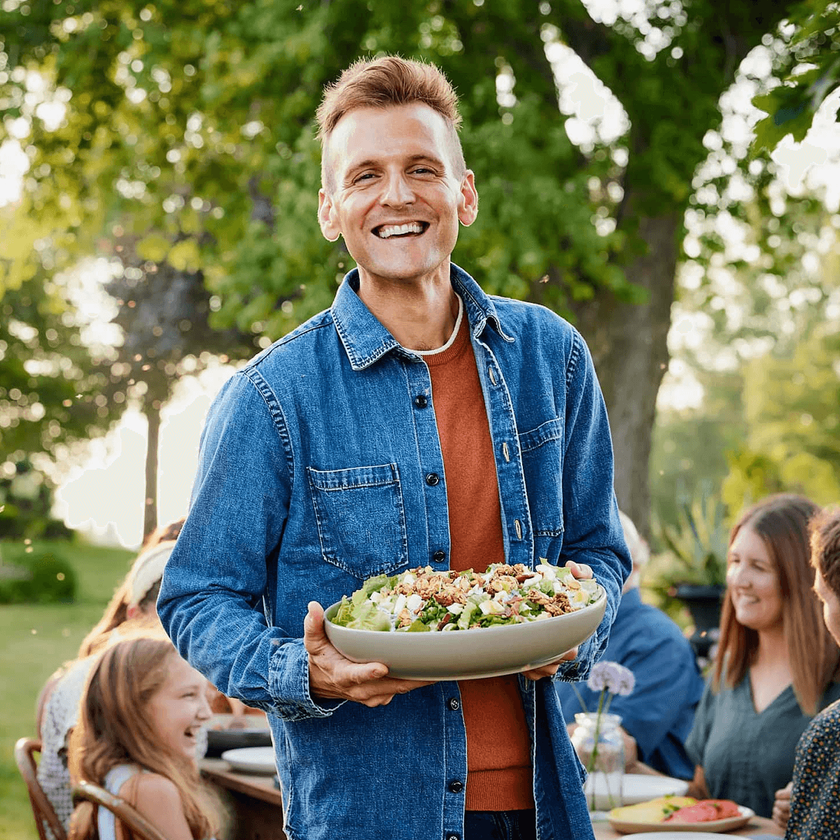 Kaleb Wyse holding bowl of salad standing in front of table with family.