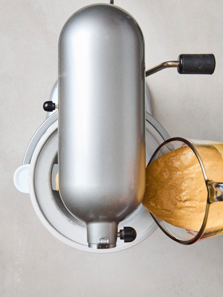 Adding pumpkin ice cream mixture to an ice cream maker.