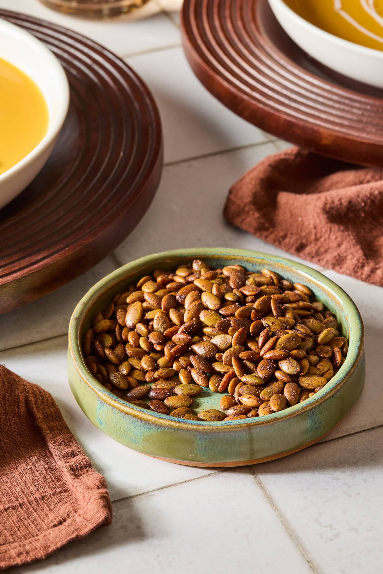 A small bowl sits on a counter filled with roasted pepitas.