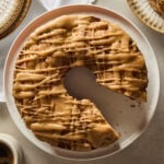 Circular apple cake with slice cut out on a cake plate with glaze on top.