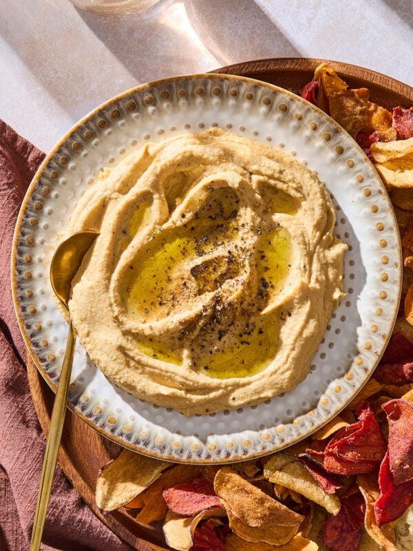 A plate with butternut squash hummus topped with black pepper and a drizzle of olive oil.