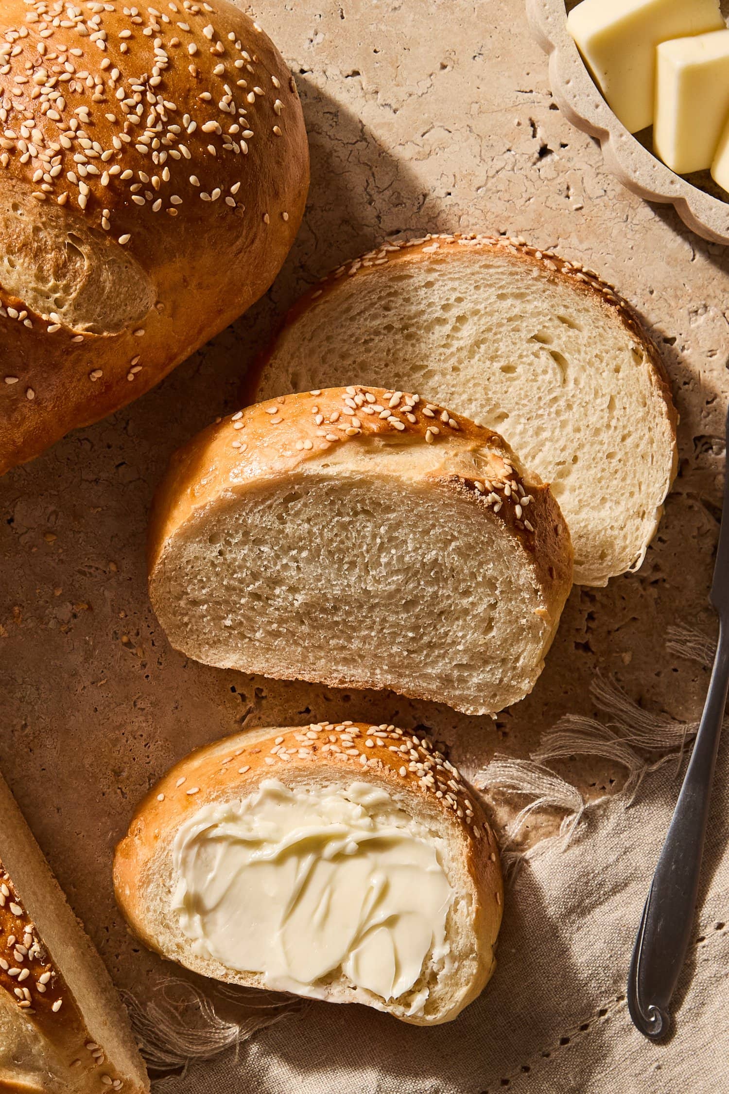 Slices of French bread on a counter topped with butter.