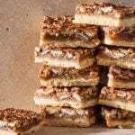 Stacks of pecan pie bars on stone surface.
