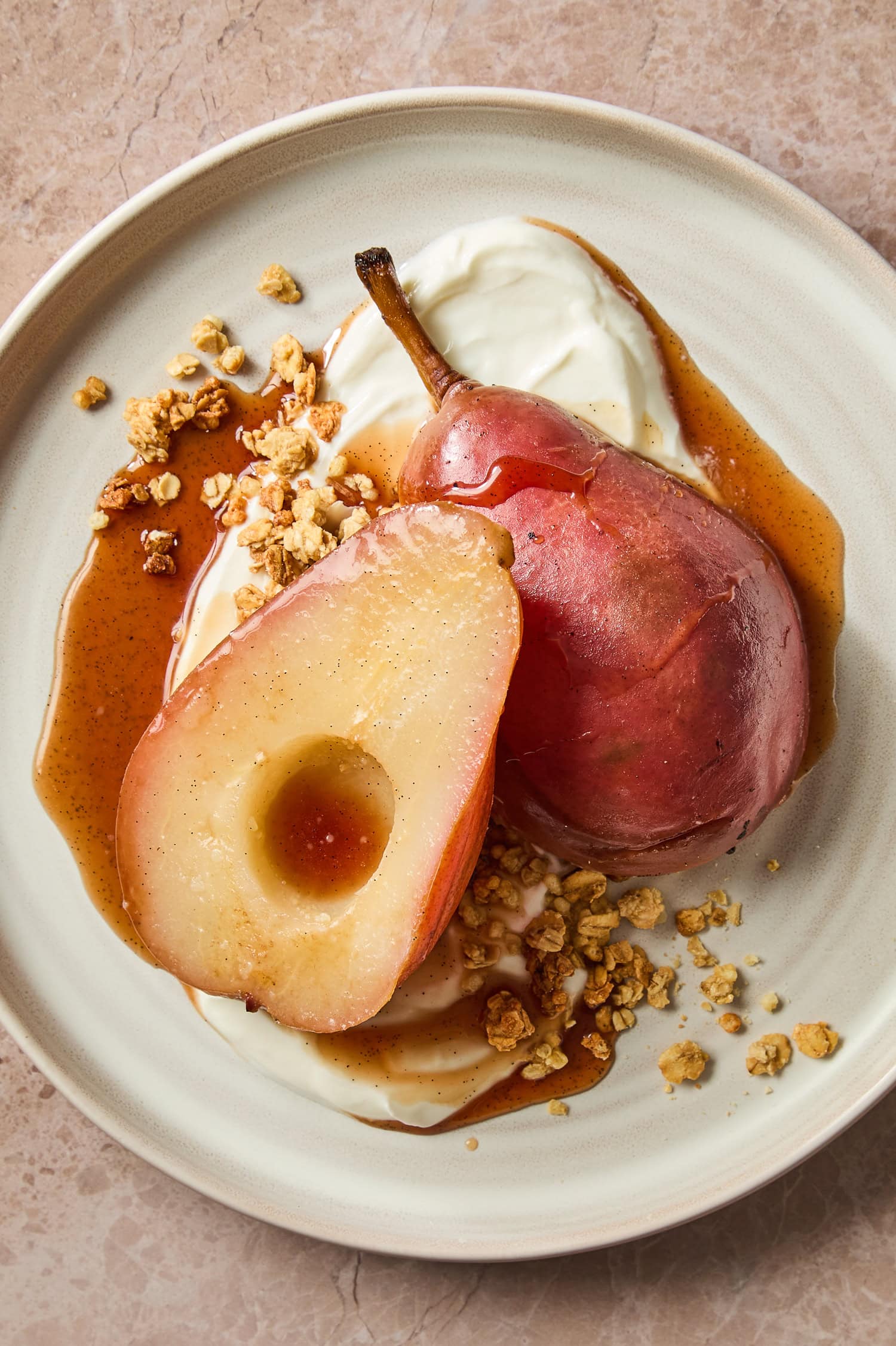 Poached pears on a plate with Greek yogurt and granola.