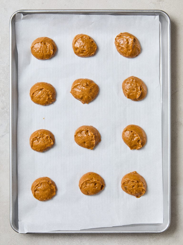 Balls of dough for pumpkin whoopie pies on a baking sheet.