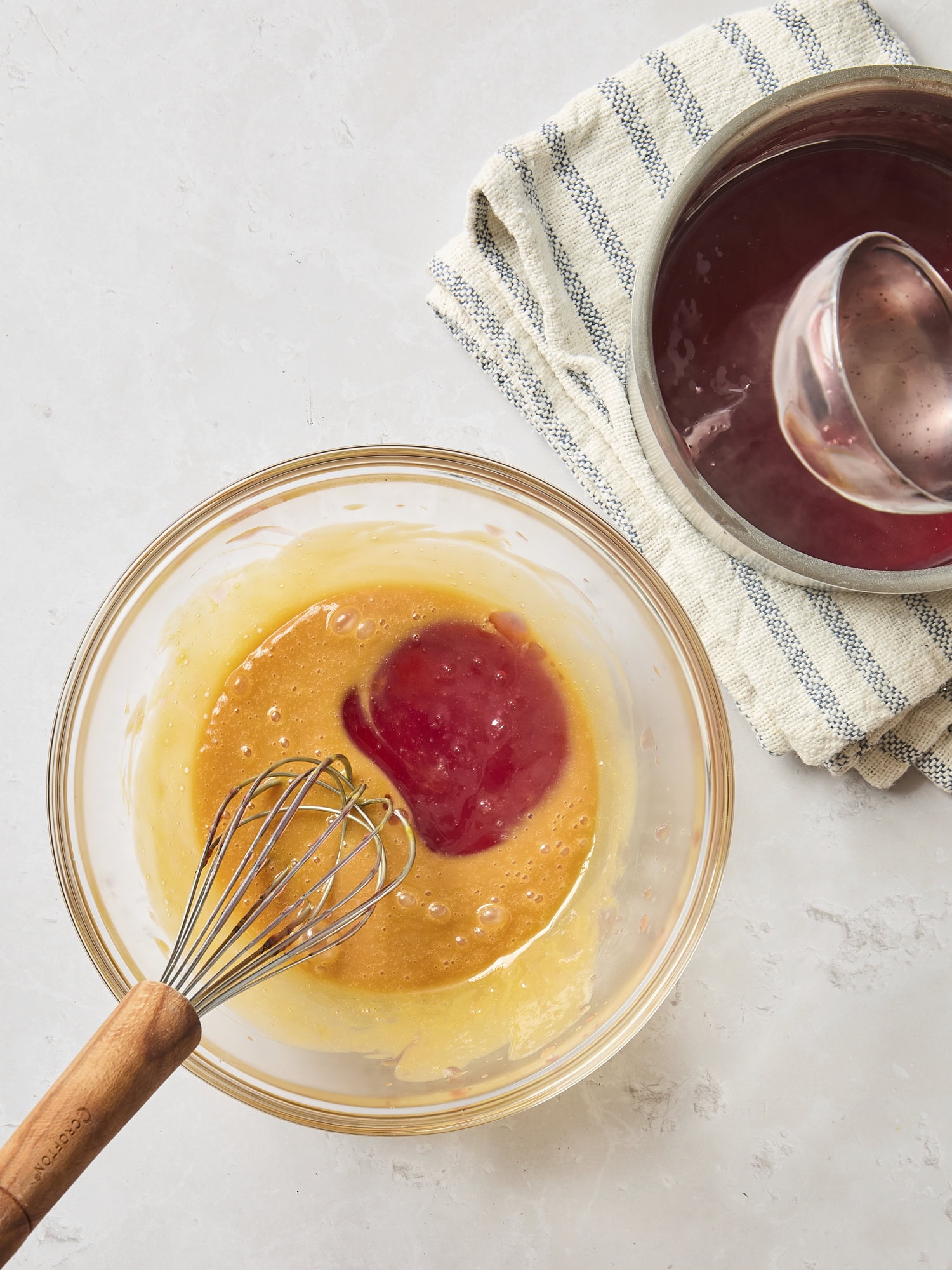 Glass bowl filled with eggs and ladleful of cranberry filling.