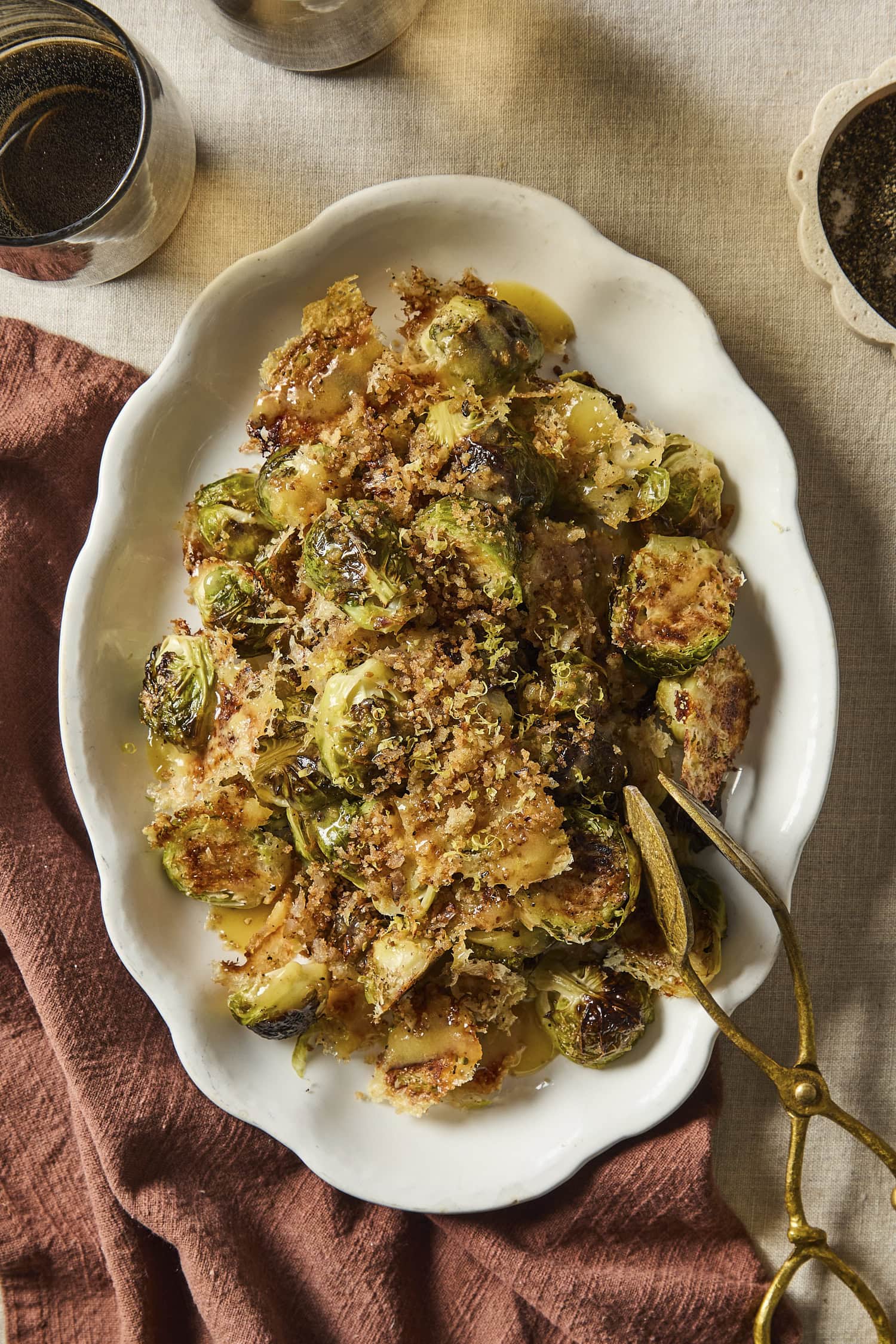 Decorative white platter filled with Parmesan roasted Brussels sprouts with crispy topping.