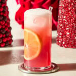 Tall glass with cranberry orange mocktail and an orange slice in the side.