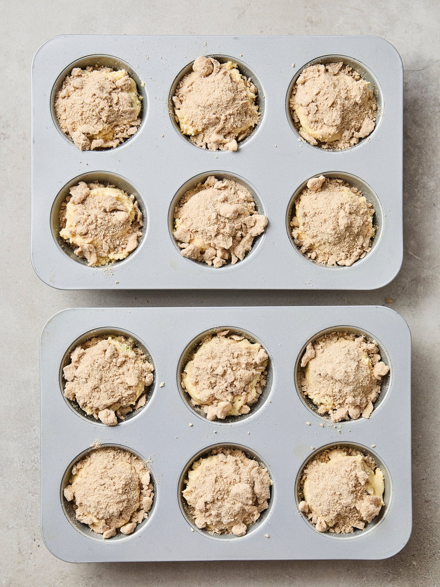 Crumb topping on top of batter in muffins tins.