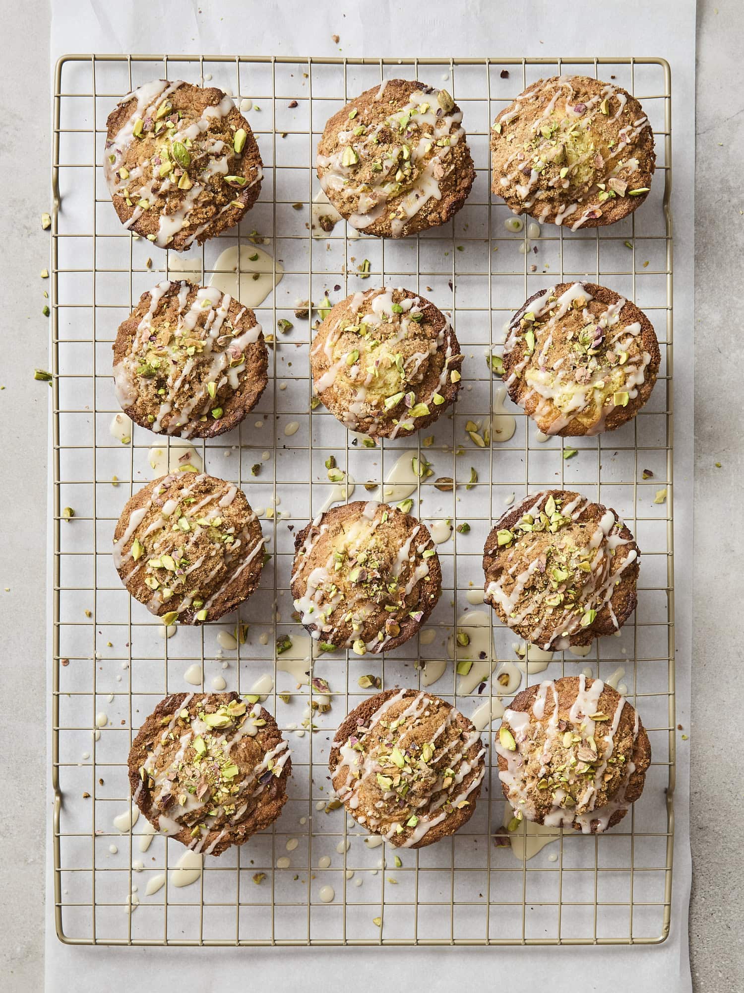 Pistachio muffins drizzled with glaze and topped with chopped pistachios.