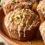 Bakery-style pistachio muffins with vanilla glaze and chopped pistachios on top.