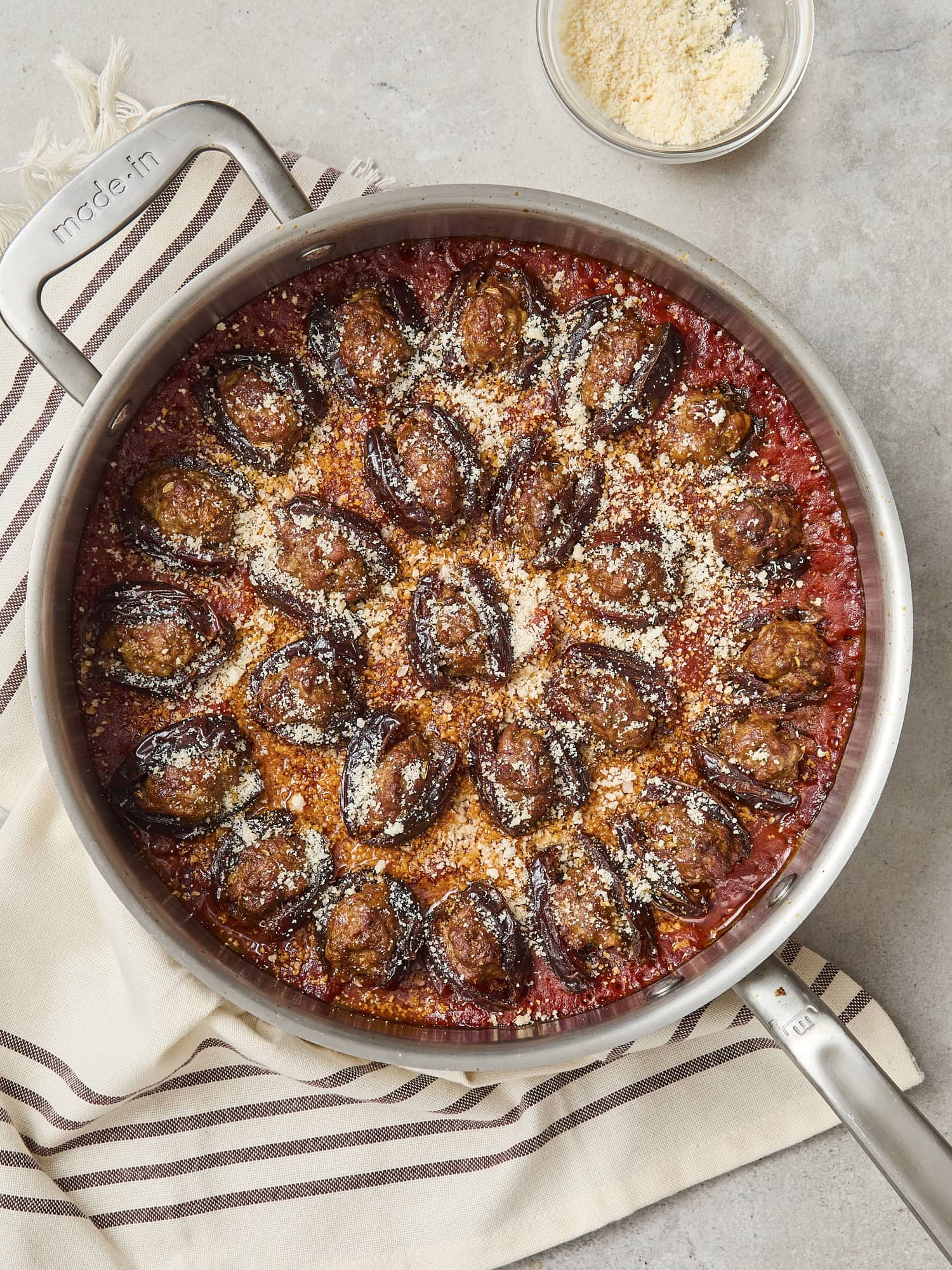 Hot pan from the oven with sausage-stuffed dates with a sprinkle of Parmesan cheese on top.