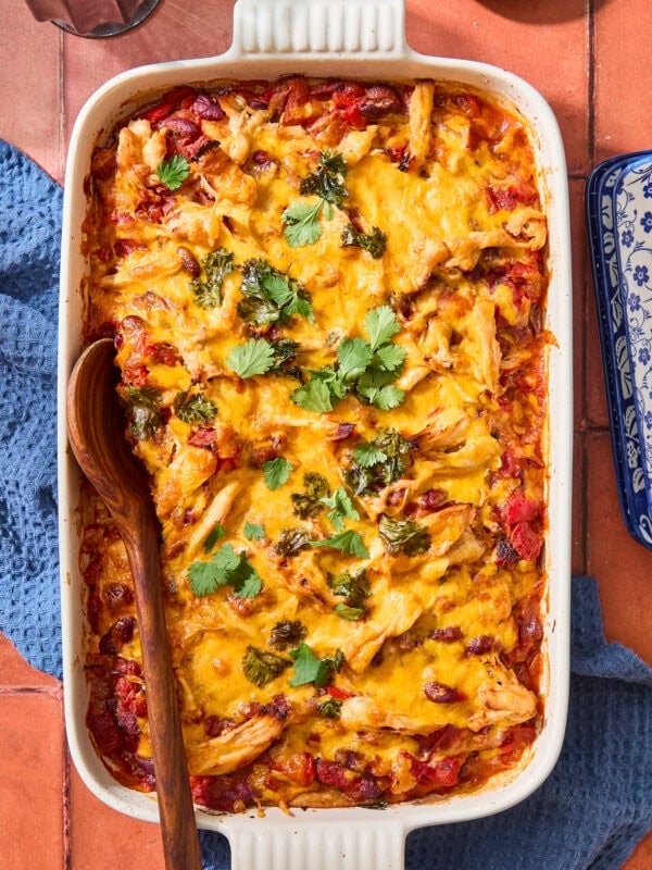 Baking pan with baked chicken tortilla casserole with cheese and cilantro sprinkled on top.