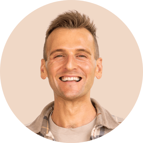 Kaleb Wyse standing in front of light tan background smiling.