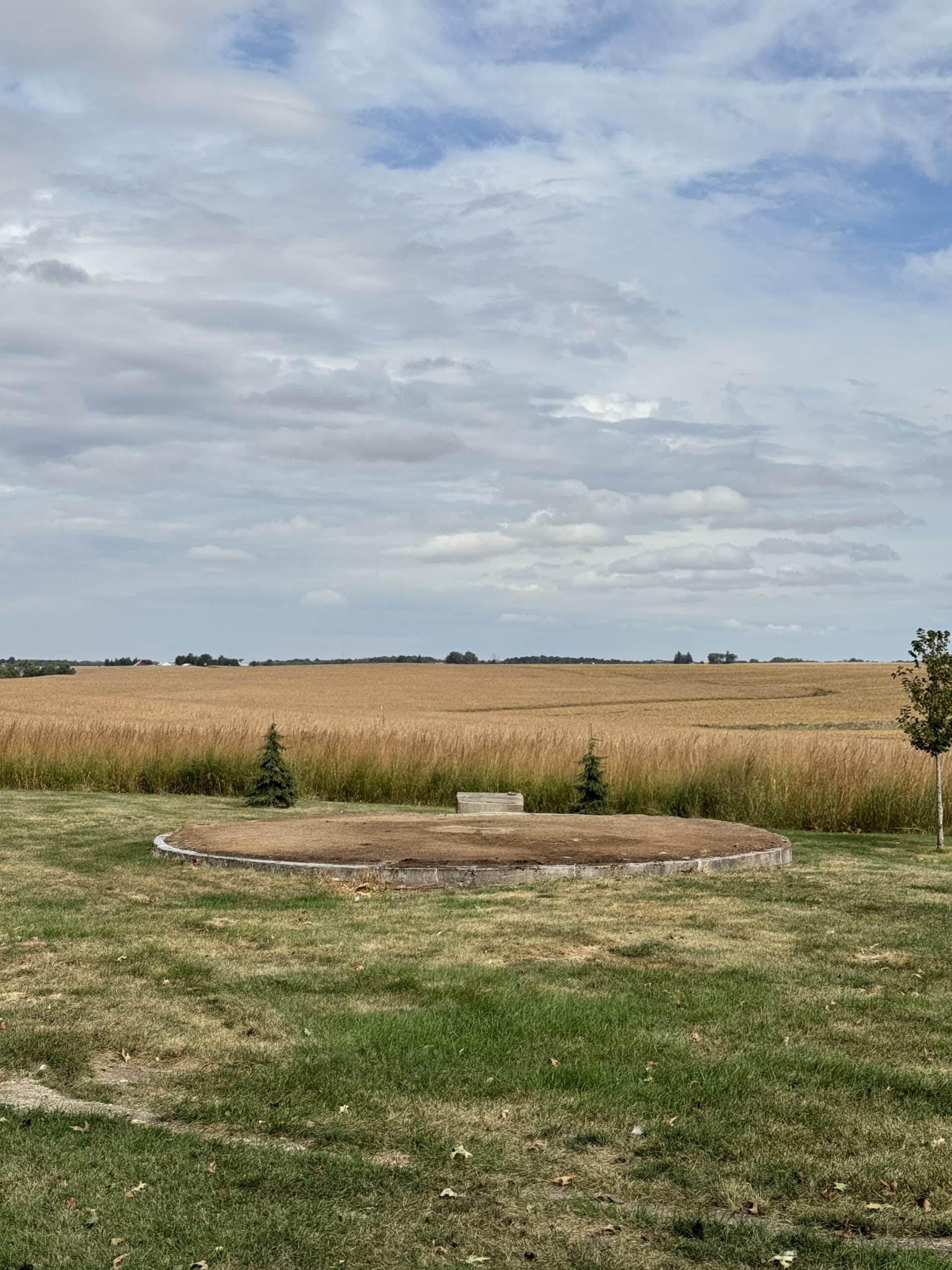 Grassy area in yard with a new dirt patch where a corn crib used to be.