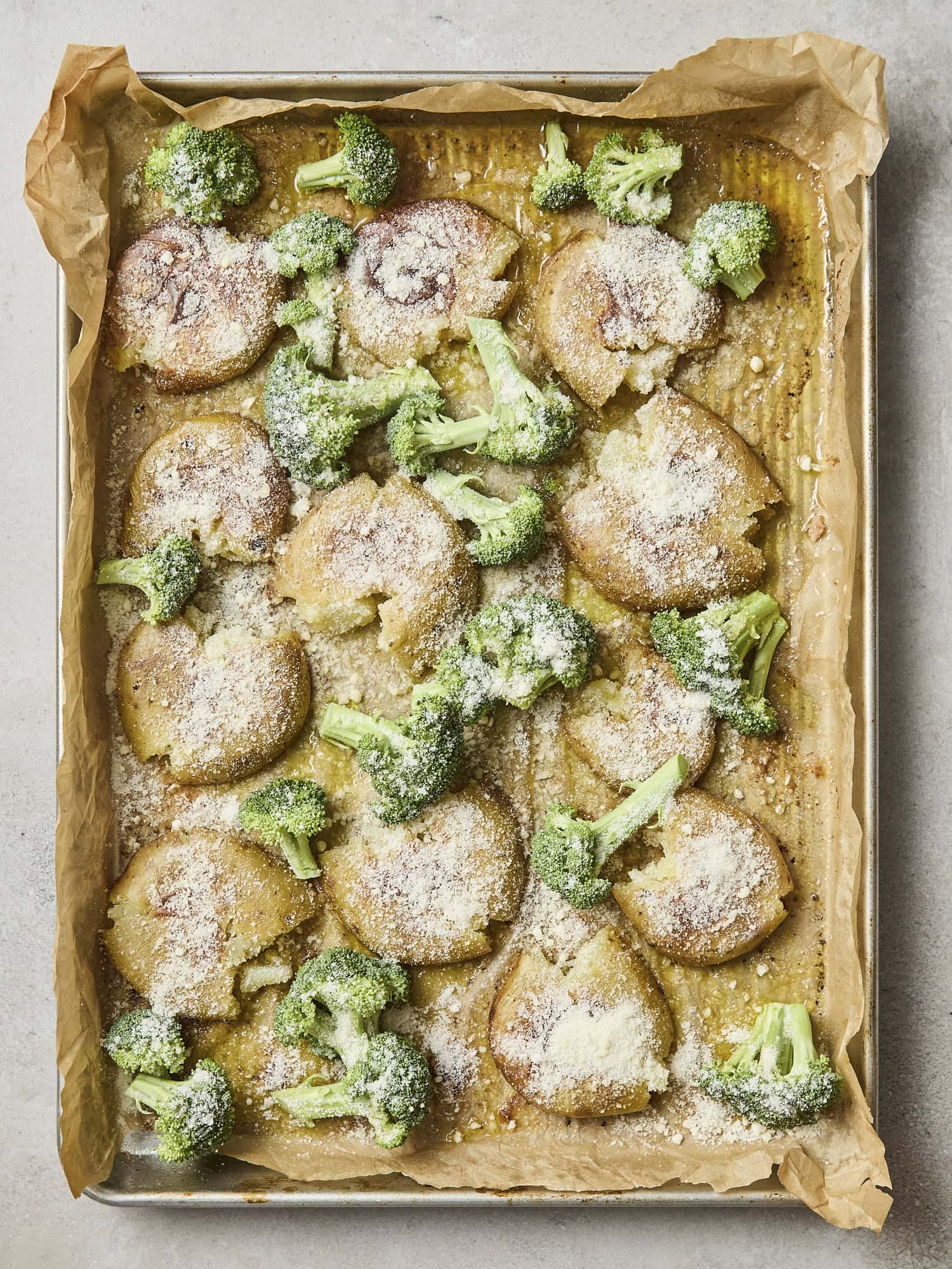 Broccoli and Parmesan added to sheet pan with smashed potatoes.