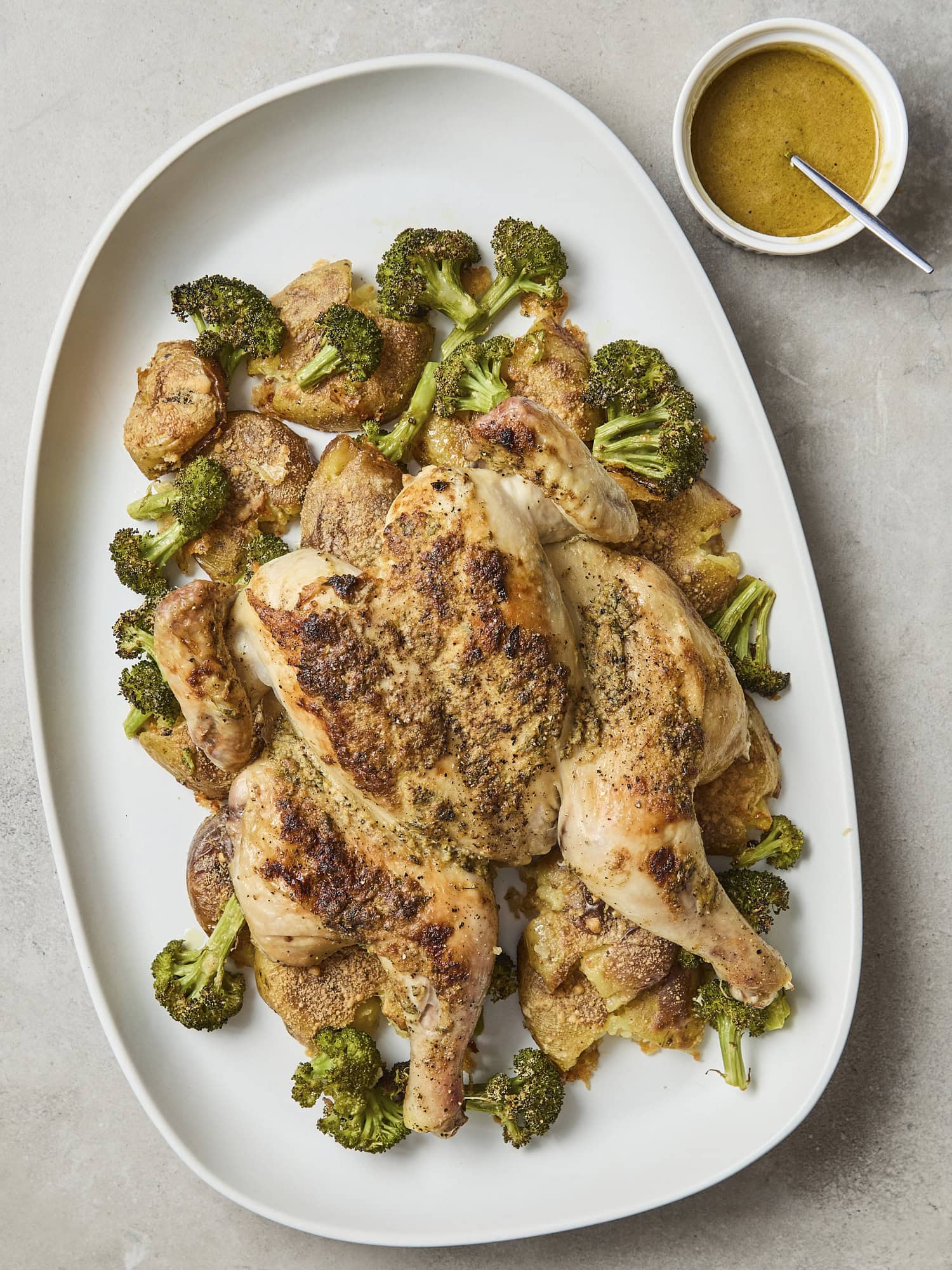 Chicken, potatoes, and broccoli on platter with vinaigrette to serve.