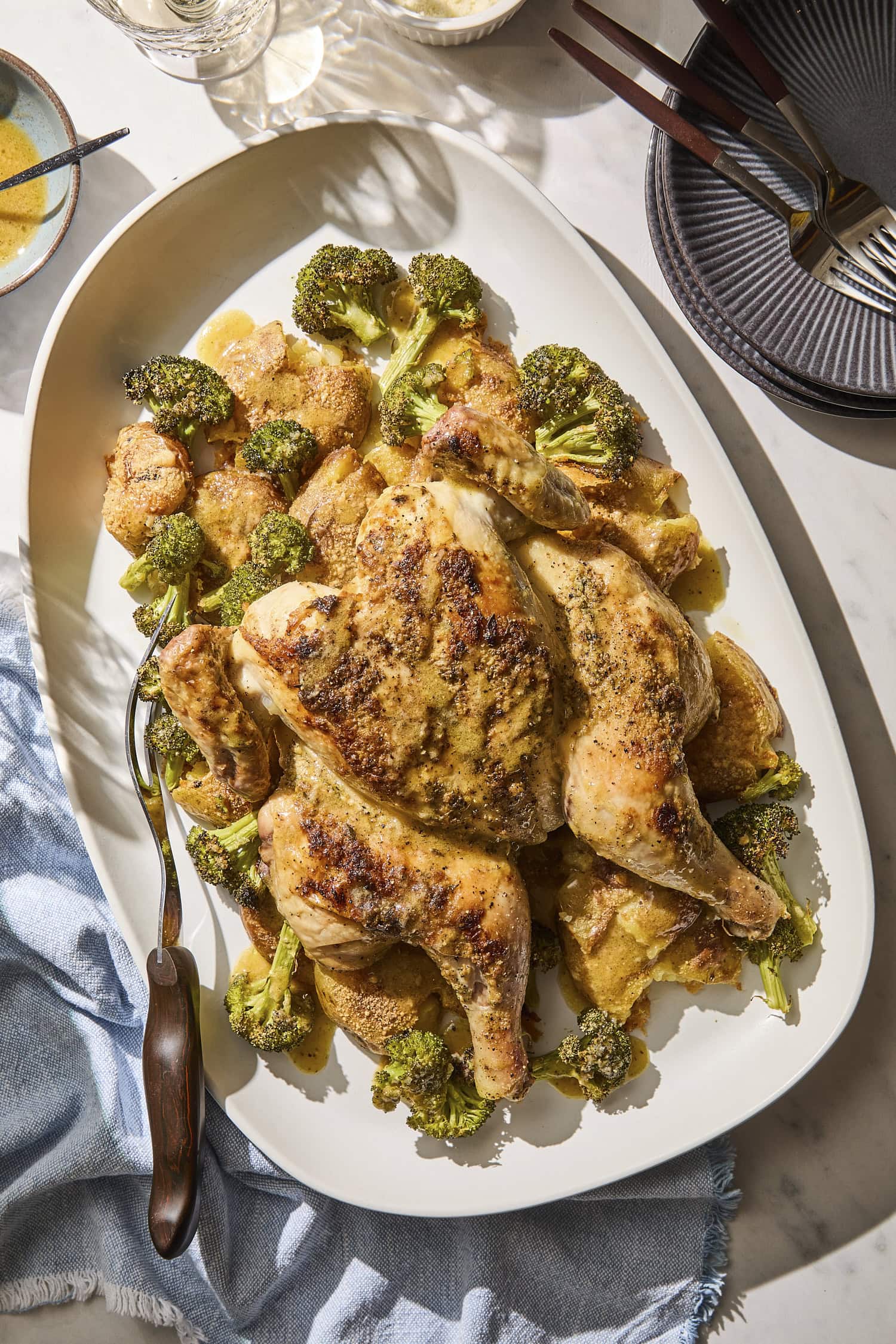Platter with sheet pan chicken and potatoes and broccoli.