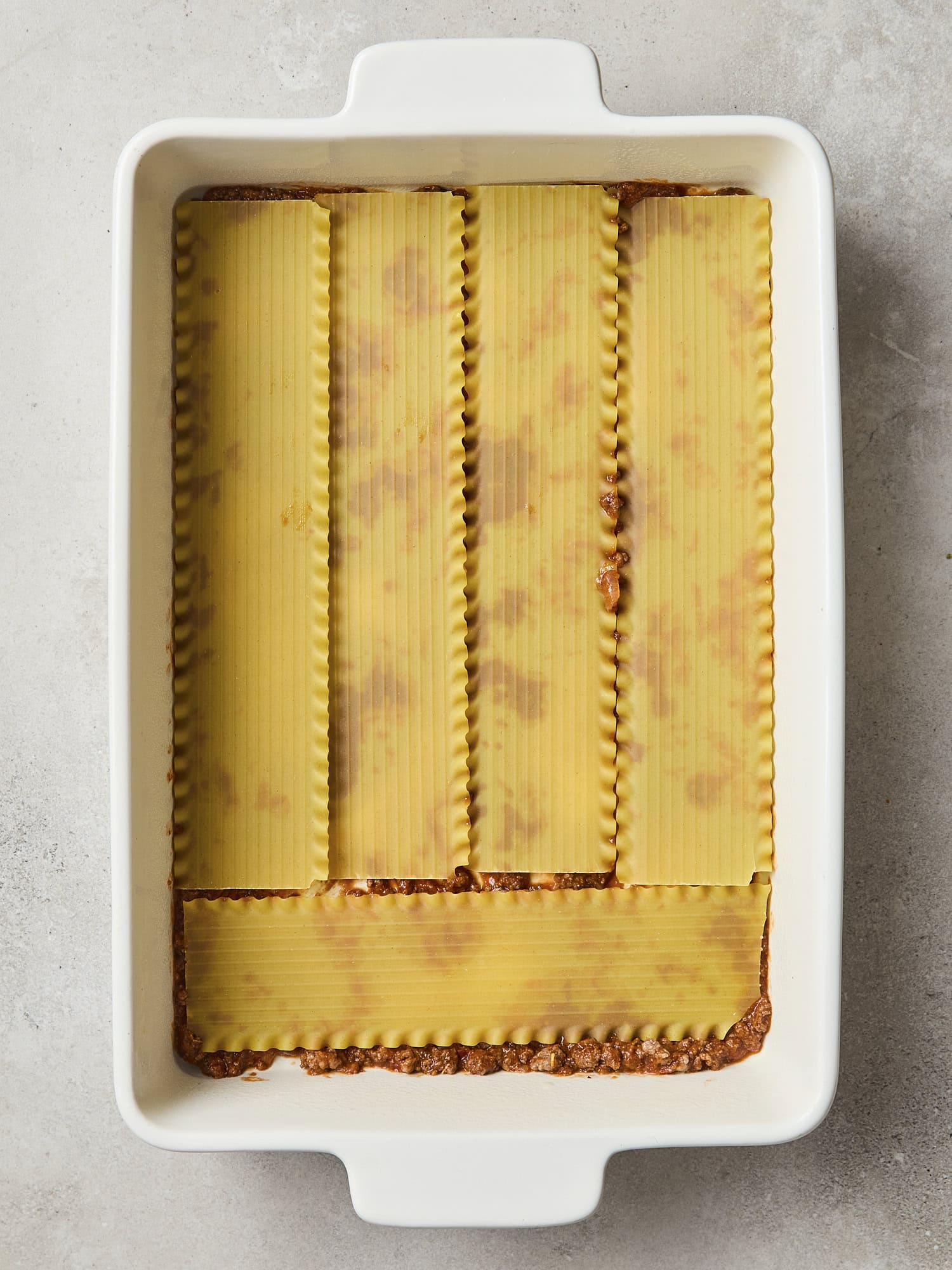 Oven-ready noodles layered for lasagna.