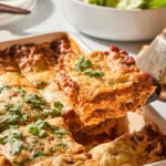 Slice of homemade lasagna being pulled from a baking pan.