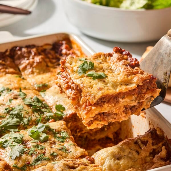 Slice of homemade lasagna being pulled from a baking pan.